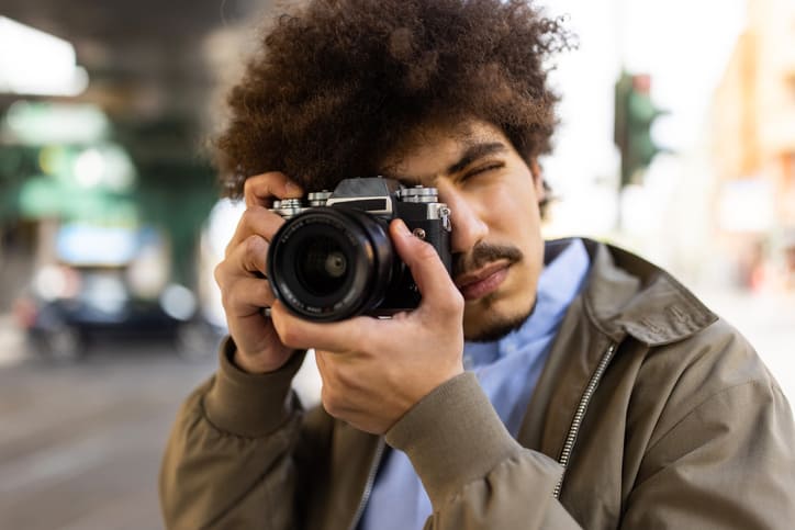 Mann mit Digitalkamera am Auge, der Fotos macht.