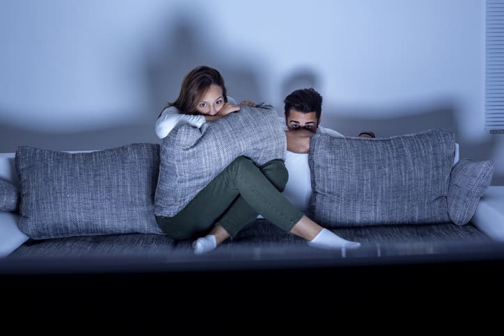 Mann und Frau verstecken sich hinter dem Sofa